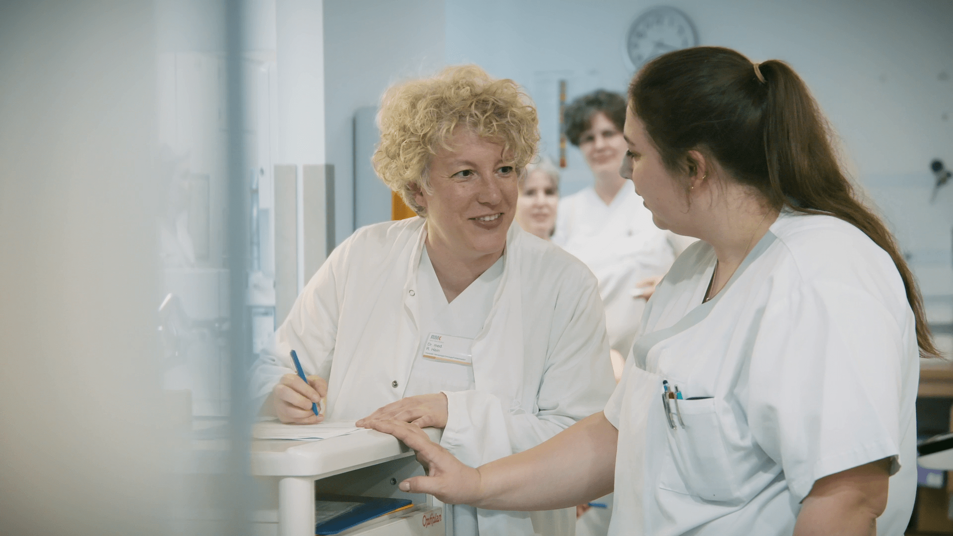 Zwei Kolleginnen auf der Palliativstation sprechen miteinander und machen Notizen